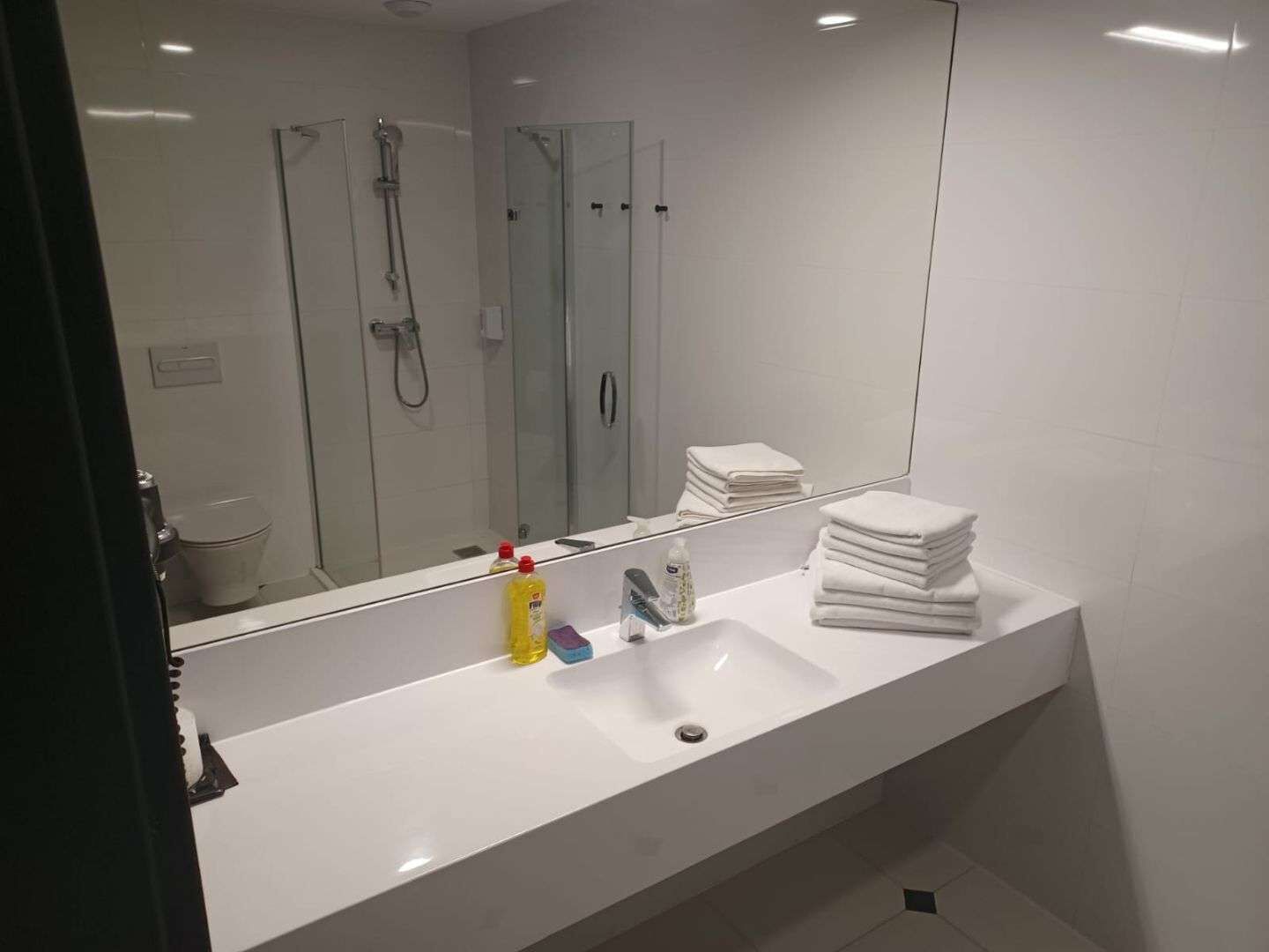 A modern bathroom with a white sink, a large mirror, and a glass shower enclosure.