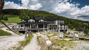 Ein modernes Hotel mit großer Glasfassade, gelegen in einer Bergregion mit Blick auf dichte Wälder.