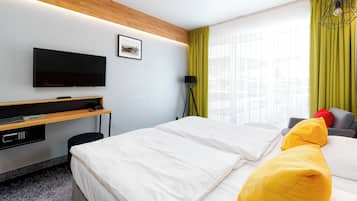 Habitación de hotel con cama, escritorio, televisor de pantalla plana, lámpara y ventana con cortinas.