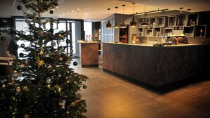 Eine moderne Hotelhalle mit einem Weihnachtsbaum, einem Empfangsbereich und einer Bar mit Glasregalen.