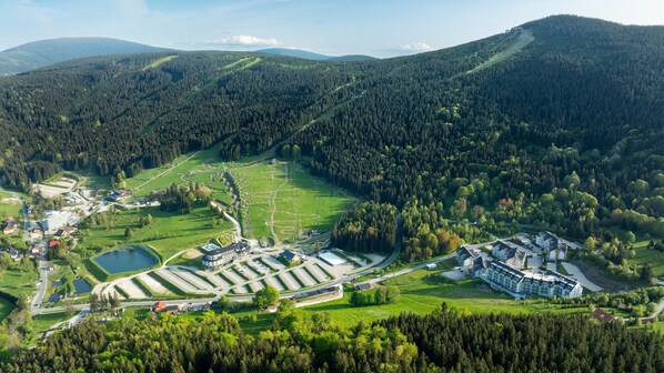 Vue aérienne d’un complexe hôtelier comprenant plusieurs bâtiments, un grand parking et un lac.