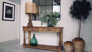 Una consola de madera con un jarrón verde, una lámpara y un espejo.