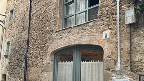 Un edificio de piedra con puerta verde y ventanas, el número 5 en la pared.