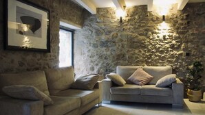 Una sala de estar con una pared de piedra, dos sofás y un cuadro enmarcado.