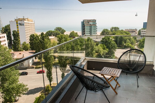 Un balcon avec vue sur la mer, une chaise et une table.