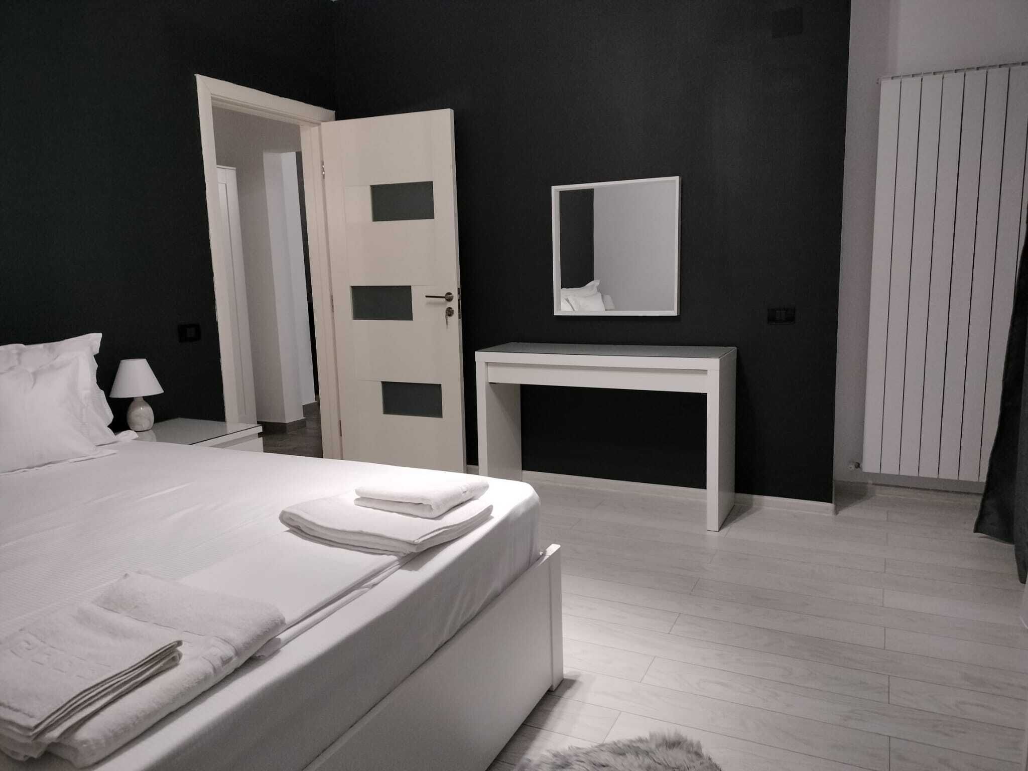 A modern bedroom with a bed, bedside table, and a white console desk.