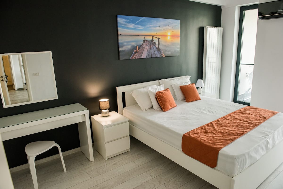 A modern bedroom with a large bed, a desk, and a nightstand.