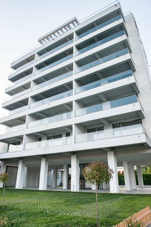 Un immeuble à plusieurs étages doté d’une architecture moderne, caractérisé par une série de balcons et de grandes fenêtres.