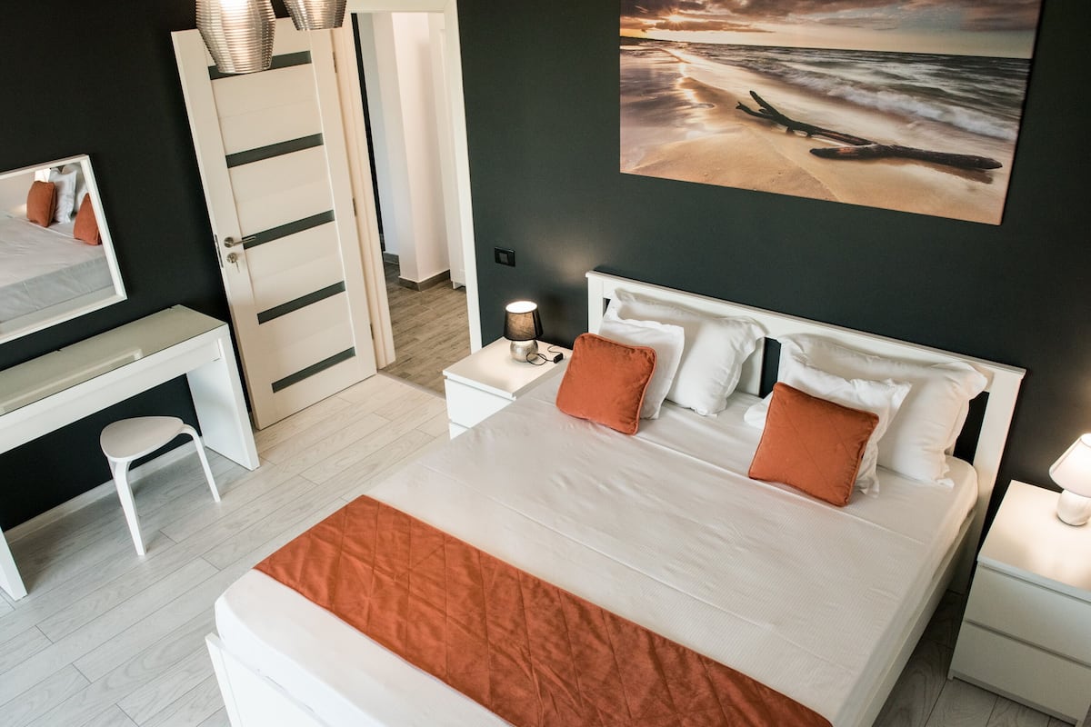 A bedroom with a bed, bedside tables, a desk, and a chair.