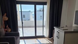 A modern living room with a sofa, a coffee table, and a TV. There is a sliding glass door leading to a balcony. - Ilya Apart 2  (Bodrum)