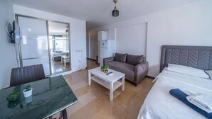 A modern hotel room with a bed, a sofa, a dining table, and a small coffee table. - Ilya Apart 2  (Bodrum)