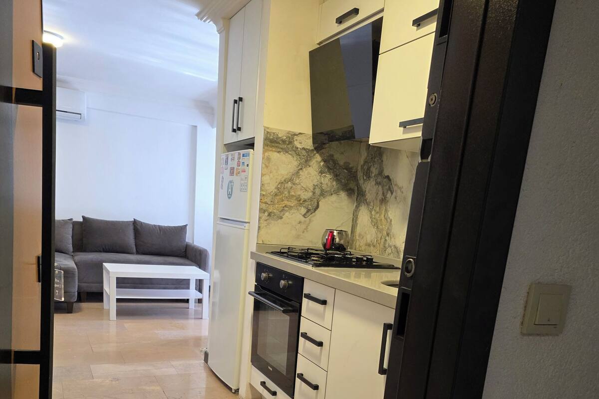 A modern kitchen with white cabinets, a marble backsplash, and a gas stove.