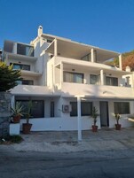 Una casa moderna de dos pisos con techo plano, ventanas amplias y base de pared de piedra.