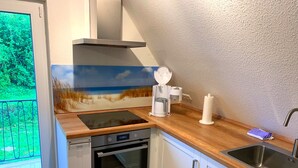 Una cocina compacta con horno integrado, cafetera y lavamanos.
