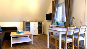 Un espacio habitable compacto con comedor, sofá, armario y televisor.