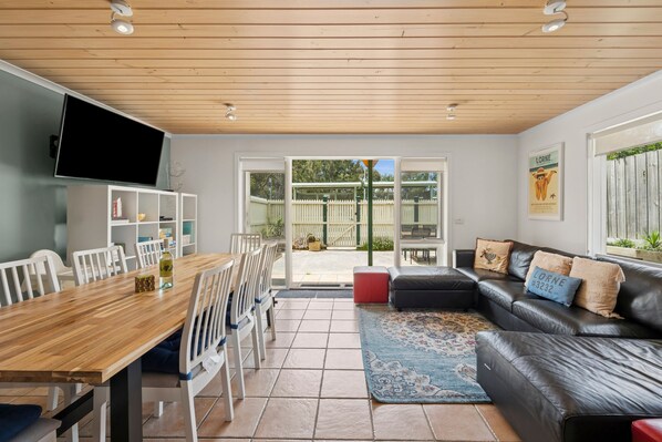 A modern living space with a dining area, a leather sofa, and a television.