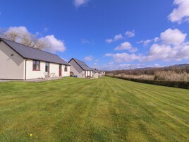 A row of single-story houses with a well-maintained lawn and a clear blue sky.