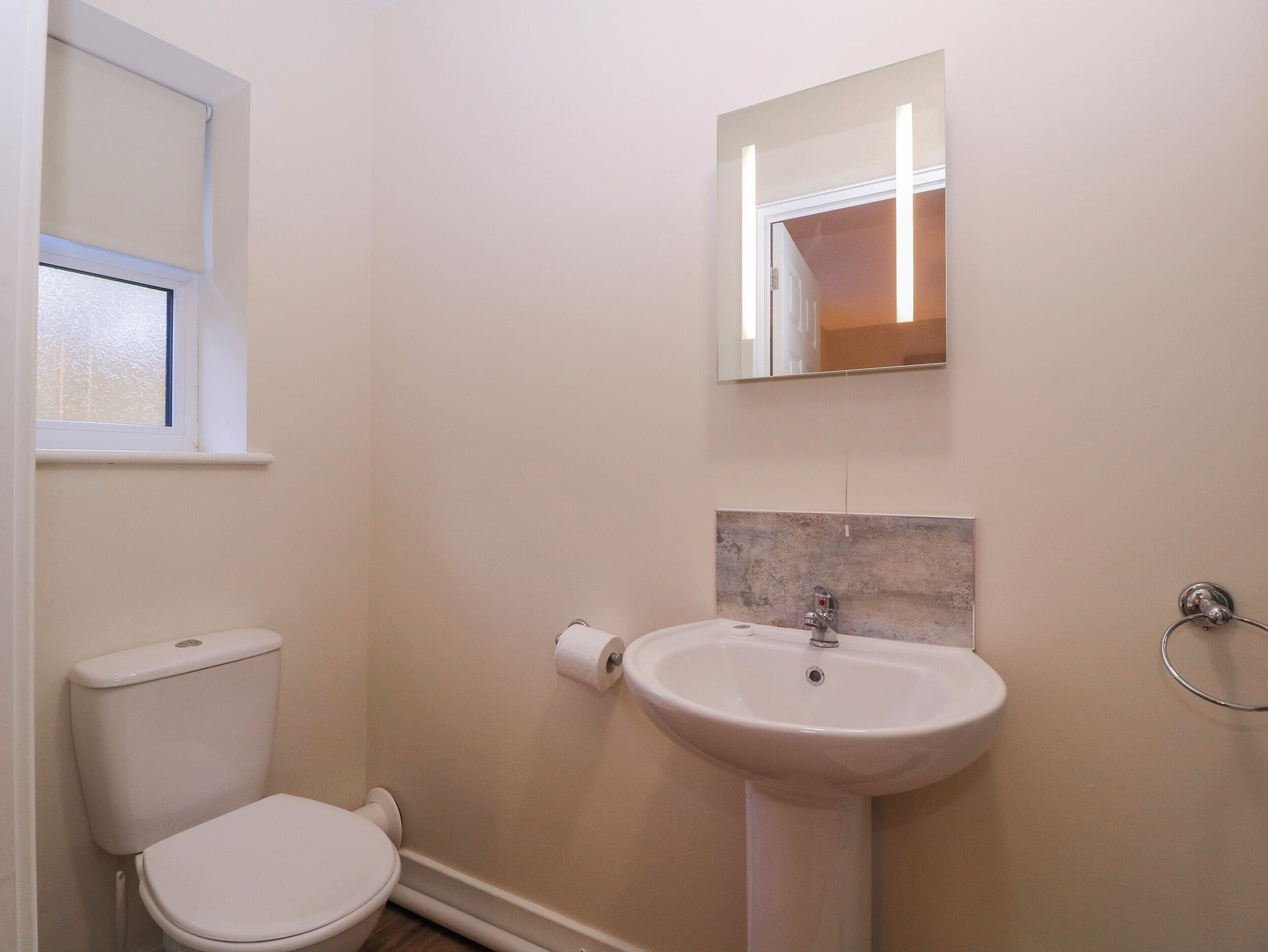 A bathroom with a toilet, sink, and mirror.