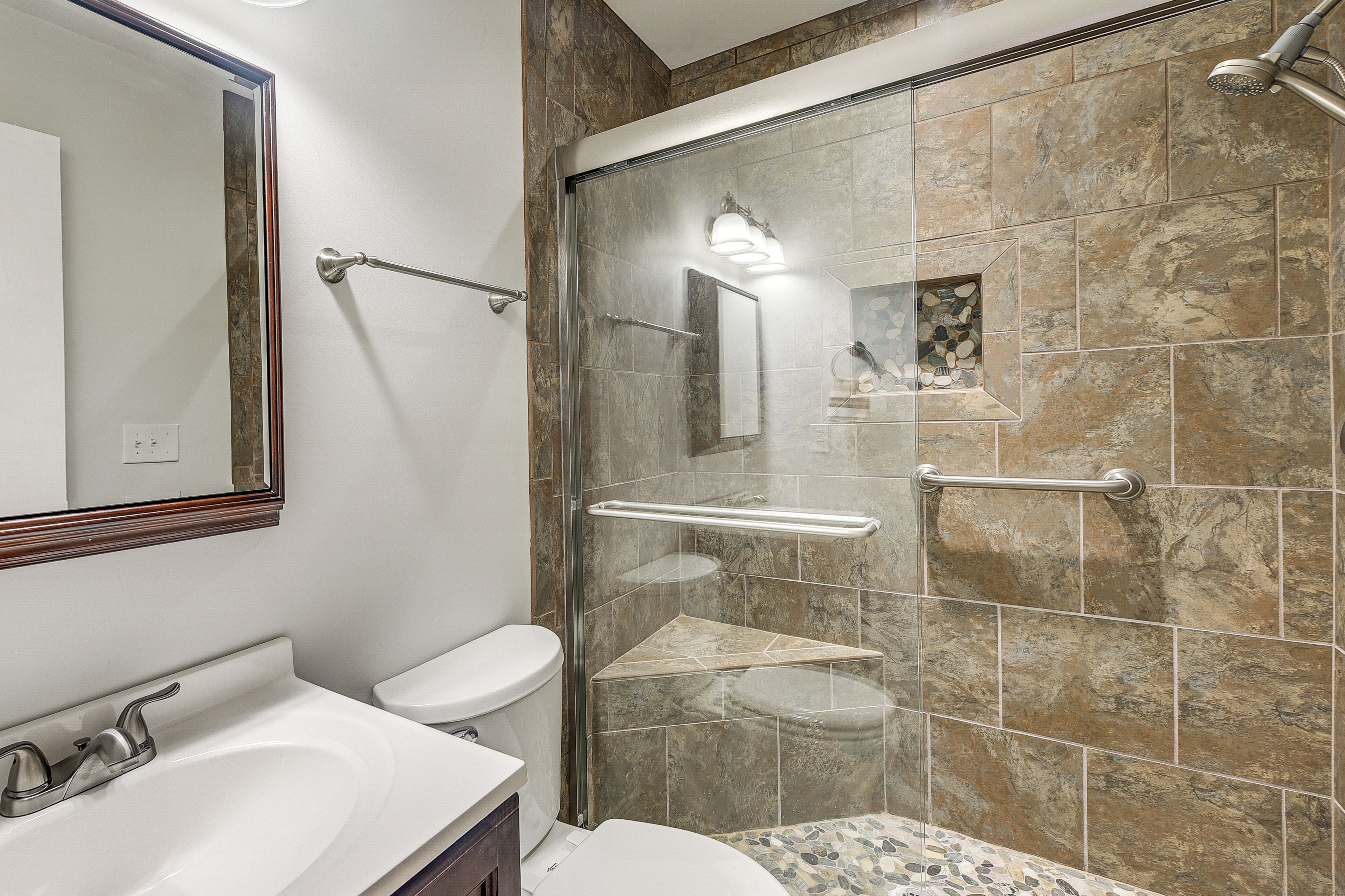 A modern bathroom with a glass-enclosed shower, a white sink, and a toilet.