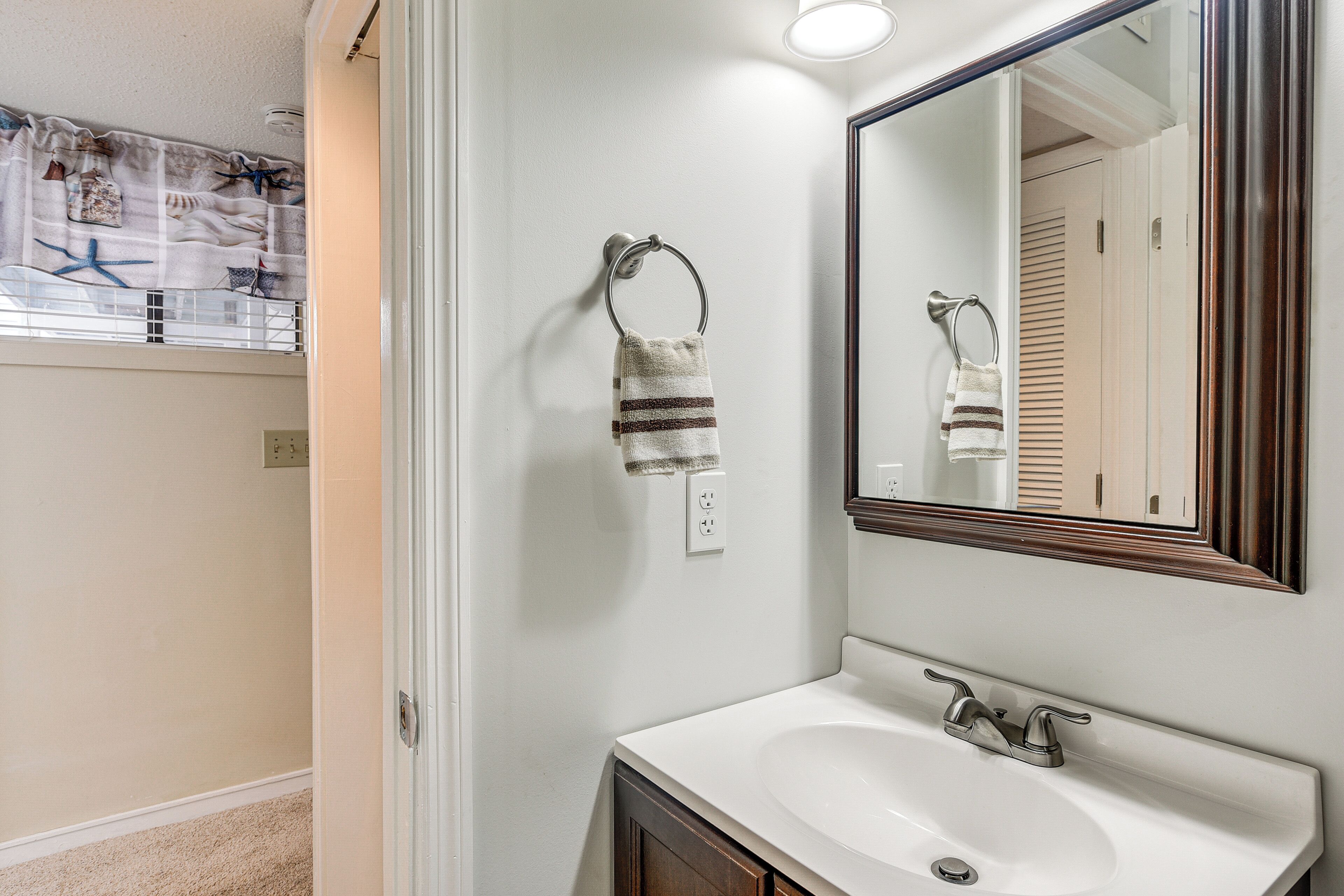 Une salle de bain avec un lavabo blanc, un miroir et un porte-serviette.