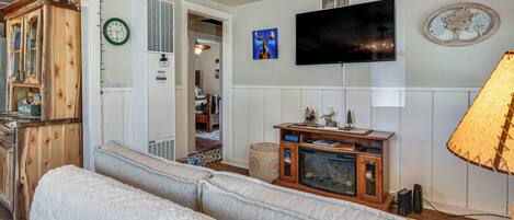 Una sala de estar con sofá, televisión y chimenea.