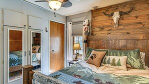 A bedroom with a large bed, a wooden headboard, a ceiling fan, and a rustic decor theme.