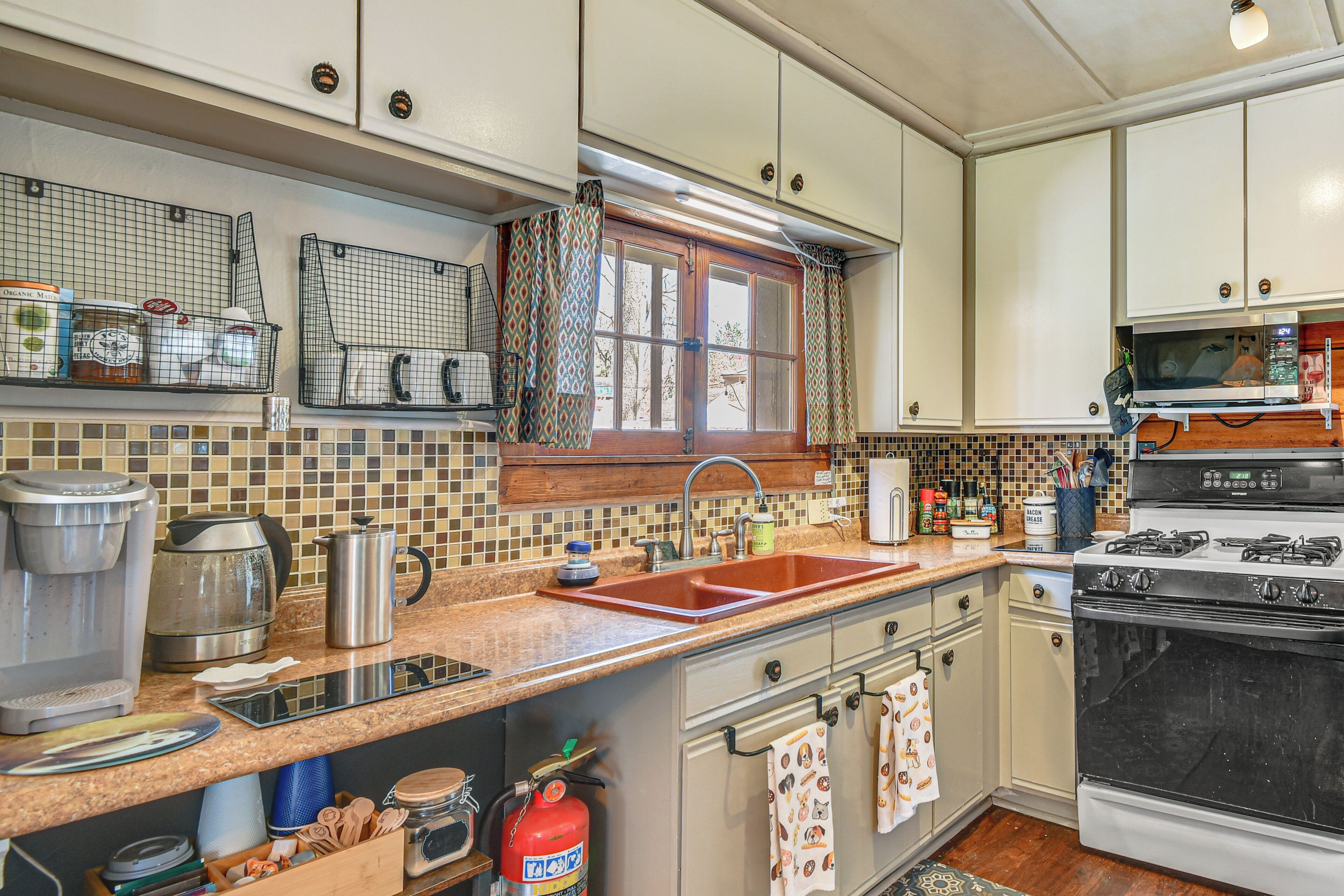 A kitchen with a sink, stove, microwave, and various appliances.