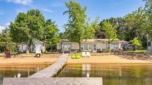 A lakeside property with a dock, beach chairs, and a boat.