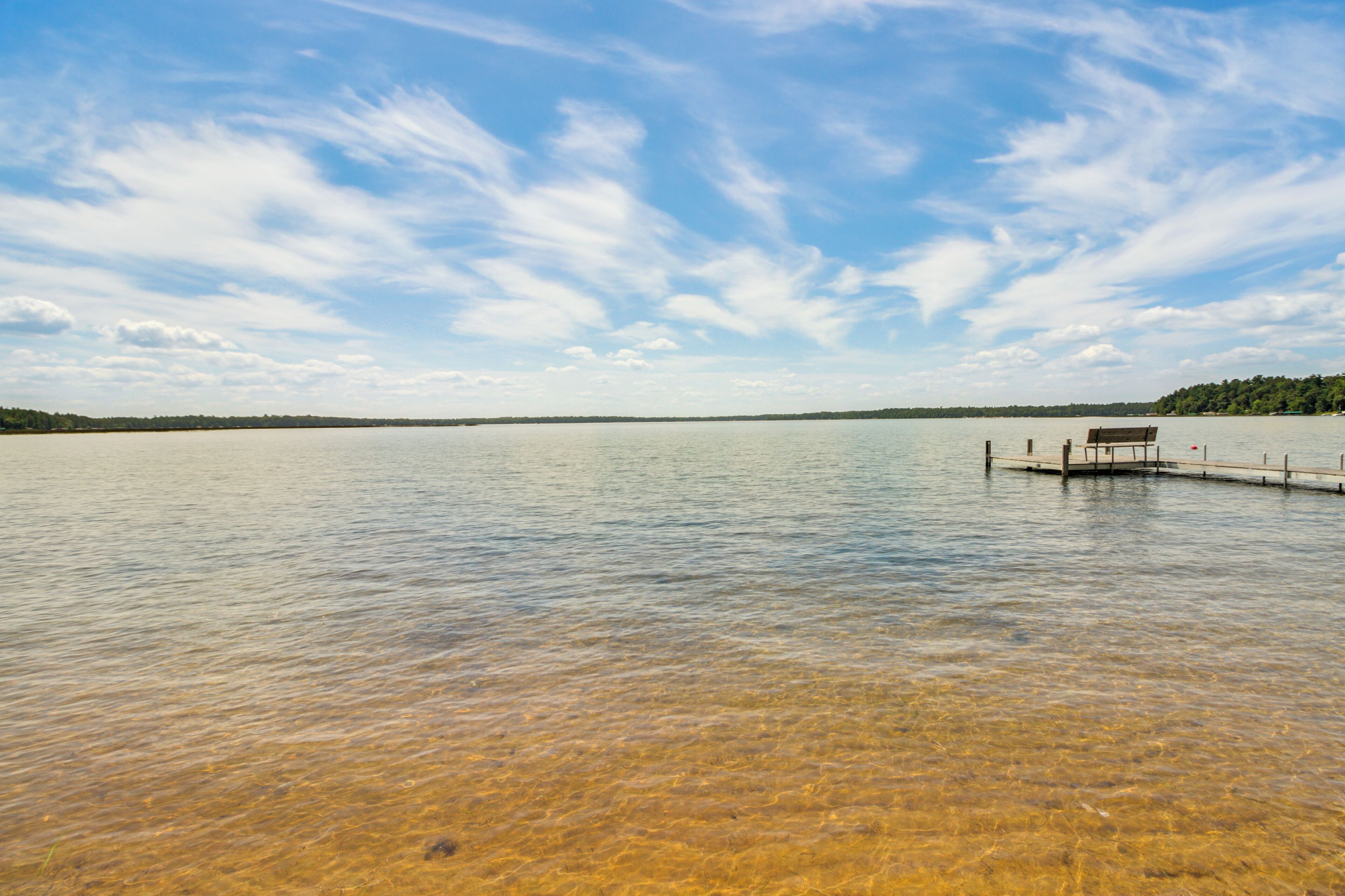Ein ruhiger See mit einer Holzsteganlage und einer Bank.