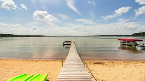 A wooden pier extending into calm water with a bench and a red canopy at the end.