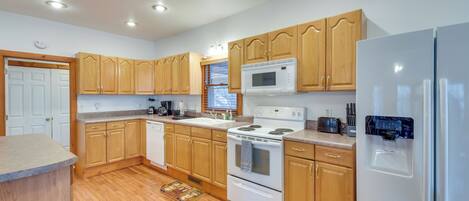 A kitchen with wooden cabinets, a white refrigerator, a stove, and a microwave.
