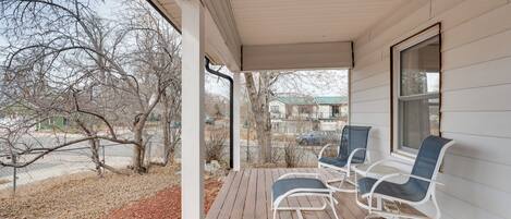 A covered porch with two rocking chairs and a window overlooking a street.