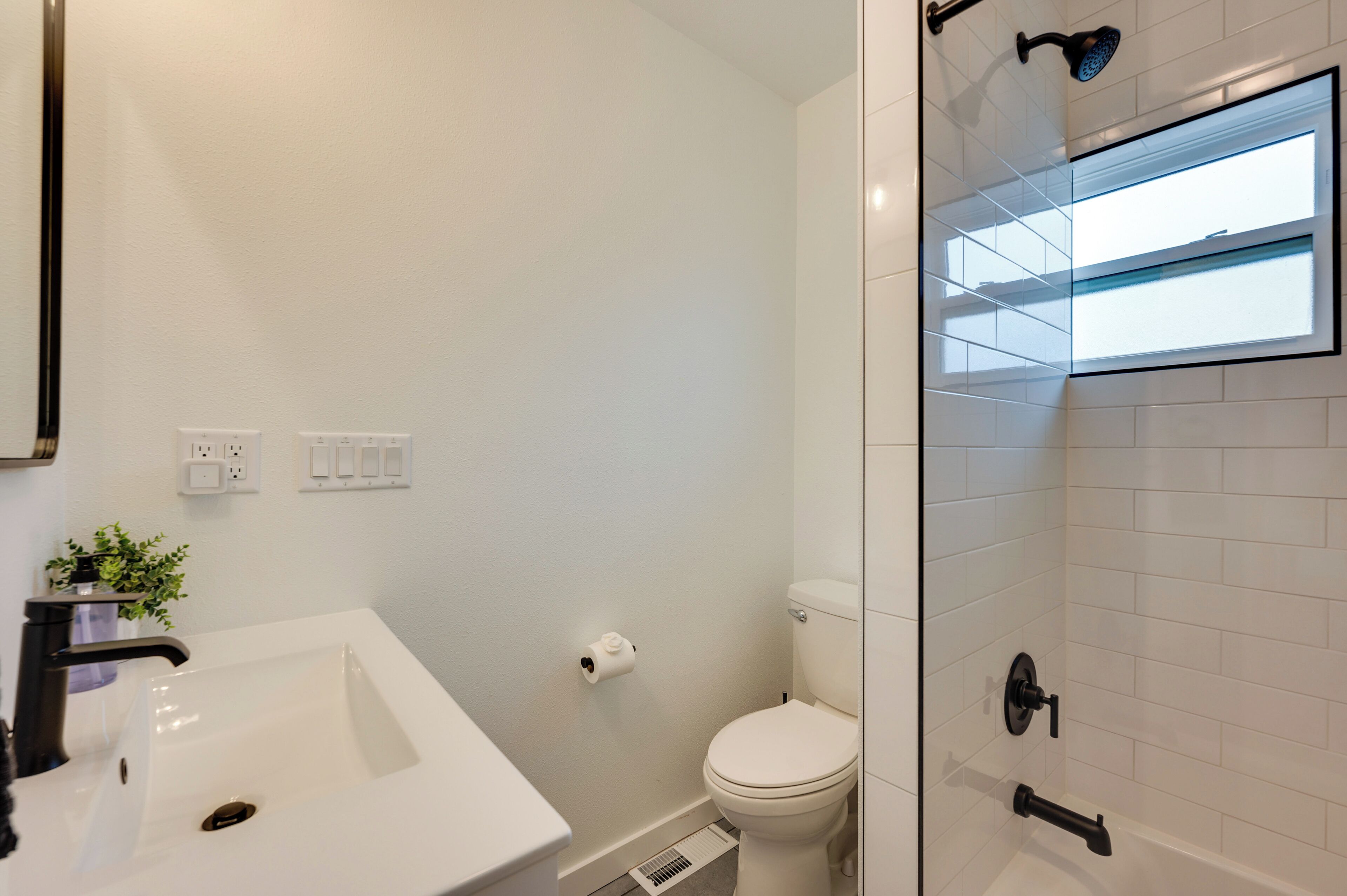 A bathroom with a white sink, toilet, and shower area.