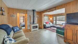 A cabin interior with a fireplace, a sofa, a television, and a wooden cabinet. - Mason Cabin w/ Private Dock on Marengo Lake! (Mason)