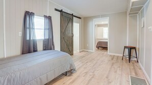 A bedroom with a bed, a sliding barn door, a small stool, and a walk-in closet. - Sun-soaked Okeechobee Retreat w/ Canal Views! (Okeechobee)
