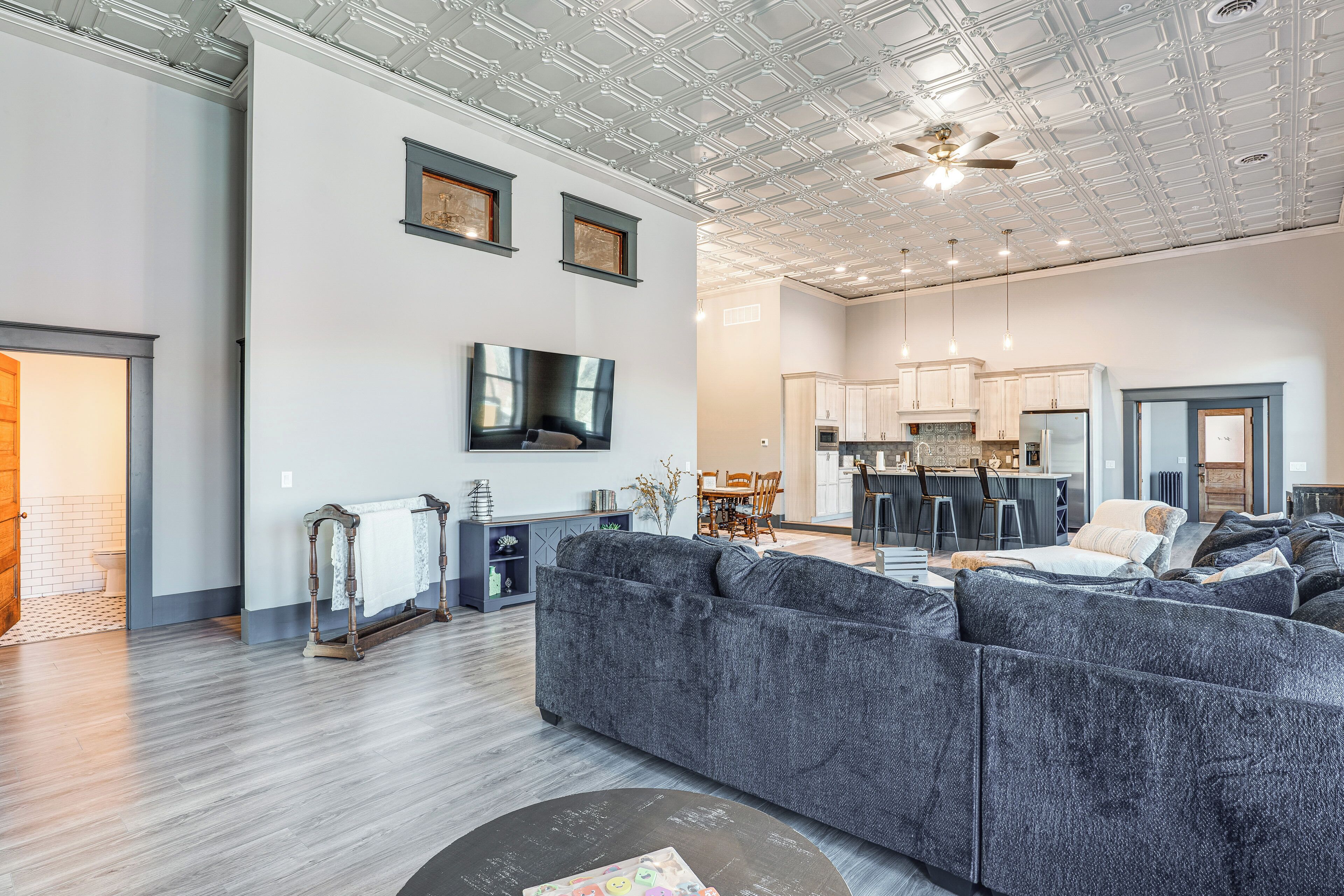 A spacious living room with a large gray sectional sofa, a wooden coffee table, and a ceiling fan.