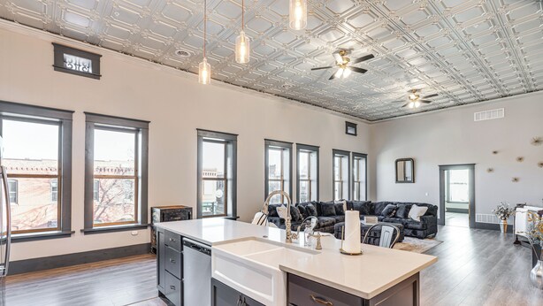 A spacious kitchen with a large island, modern appliances, and large windows offering views of the city. - Florence Vacation Rental w/ Rooftop Deck! (Florence)
