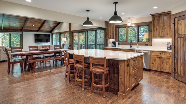 Una cocina amplia con una isla grande, armarios de madera y un comedor con una mesa larga y sillas.