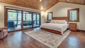 Un dormitorio con una cama grande, techo de madera y un ventanal corredero que da a un patio exterior.