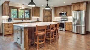 Una cocina moderna con armarios de madera, electrodomésticos de acero inoxidable y una isla grande con taburetes de bar.