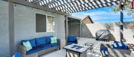 An outdoor patio with wicker furniture, a pergola, and a barbecue grill.