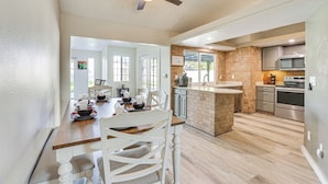 A spacious kitchen with a brick island, modern appliances, and a dining area with a wooden table and white chairs. - Peoria Home w/ Private Pool, Hot Tub, & Gas Grill! (Peoria)