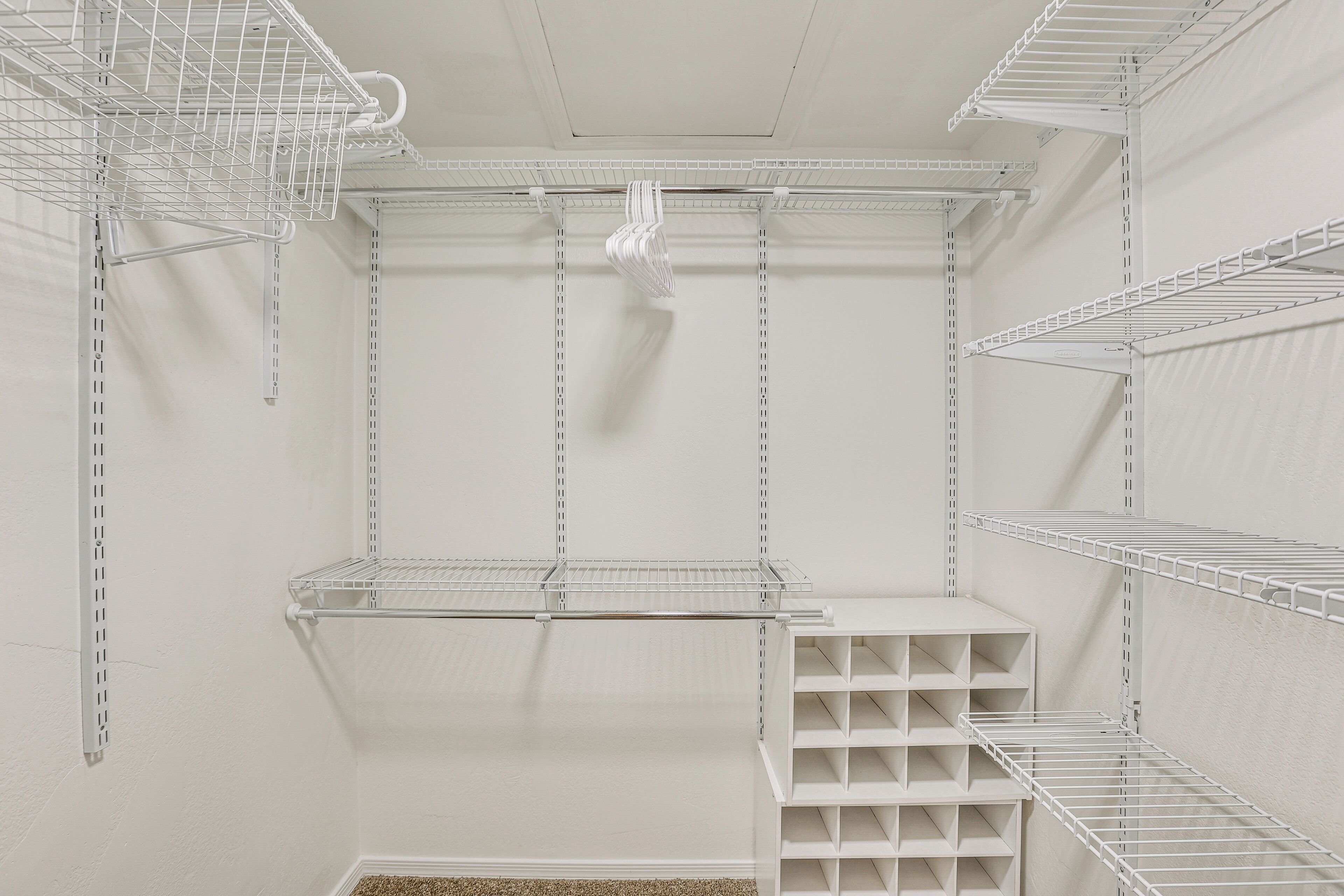 Ein weißer Kleiderschrank mit mehreren Einlegeböden und Platz zum Aufhängen.