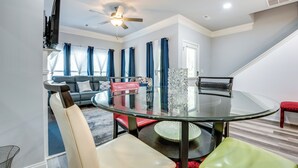 A modern living room with a glass dining table, red and green chairs, a sofa, and a TV. - Atlanta Home w/ Patio, 8 Mi to Downtown + Aquarium (Atlanta)