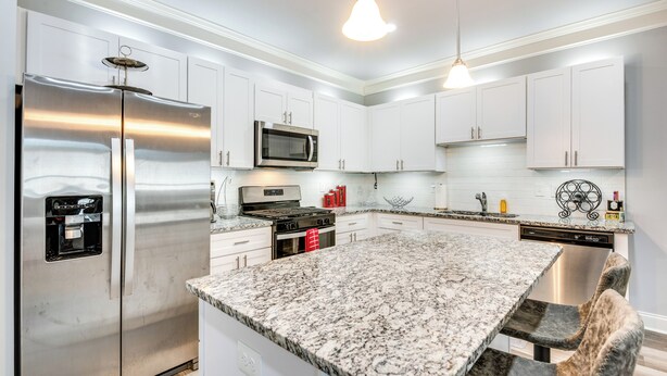 A modern kitchen with stainless steel appliances, white cabinets, granite countertops, and pendant lighting. - Atlanta Home w/ Patio, 8 Mi to Downtown + Aquarium (Atlanta)