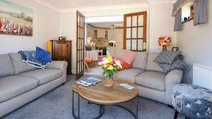 A living room with two grey sofas, a wooden coffee table, and a painting on the wall. - Lavender Cottage (Hailsham)