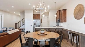 A modern kitchen with a central island, wooden cabinets, and a chandelier.