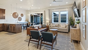 A spacious living area with a sofa, chairs, a coffee table, and a TV mounted on the wall.