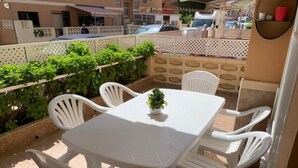 Eine kleine Terrasse im Freien mit einem weißen Tisch und vier weißen Stühlen.