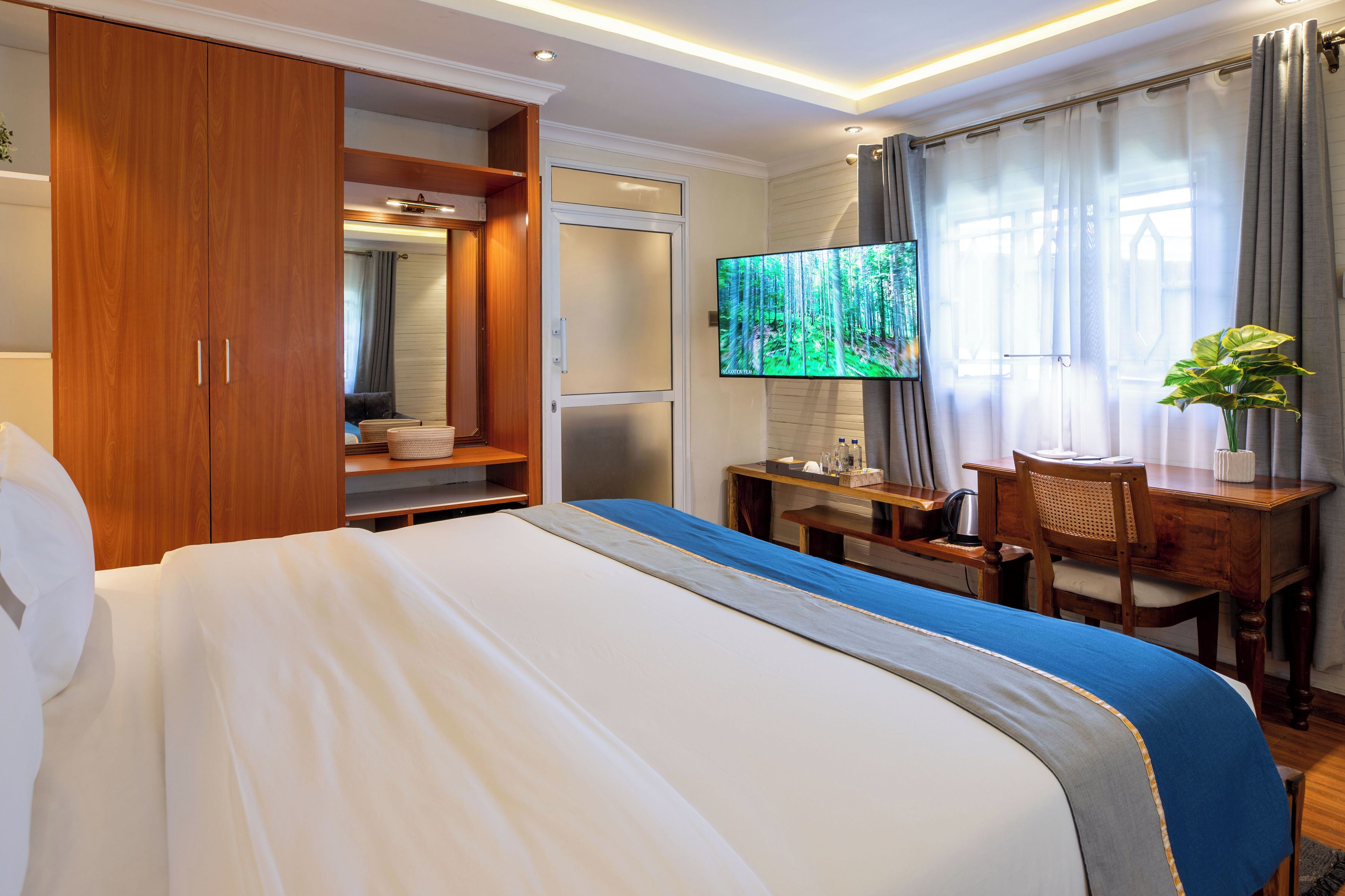 Une chambre d’hôtel avec un lit, un bureau, une télévision et une armoire.